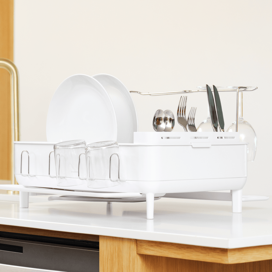 Angled view of Simplehuman White Steel Frame Dishrack, fully loaded with dishes, removable utensil caddy, and wine glass rack.