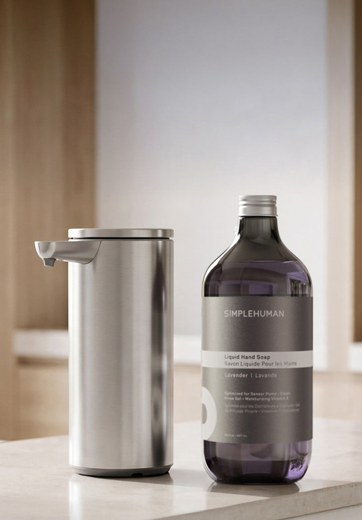 Brushed stainless steel Sensor Pump with lavender liquid hand soap refill on a bathroom counter.