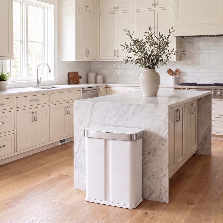 Simplehuman's 58L Sensor Recycler in white in a modern kitchen setting with marble countertops and white cabinets.