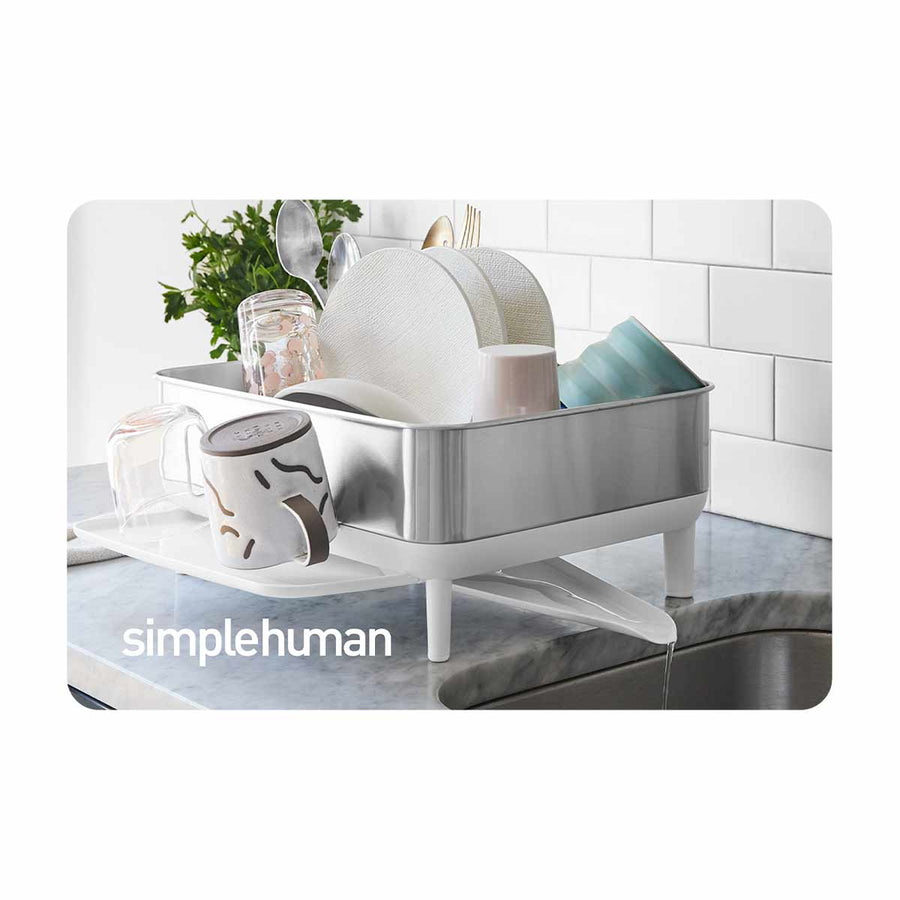 Simplehuman Dishrack in Stainless Steel and White, draining water directly into the sink for drip-free drying.